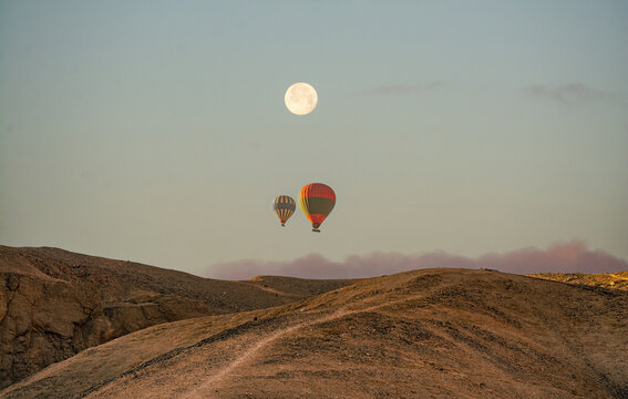 Hot air balloon flying over the desert in full moon sky