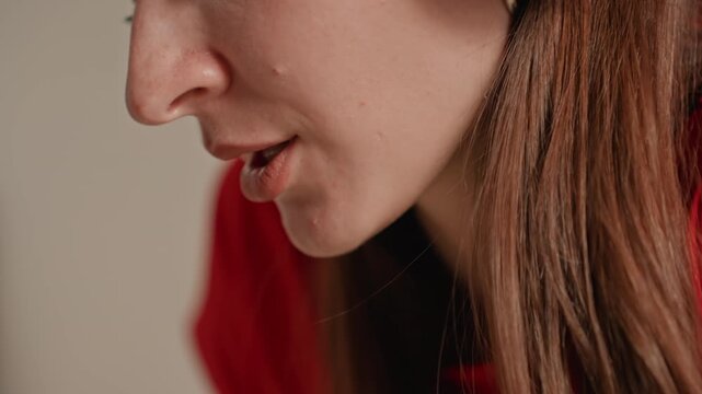 Intimate closeup white woman home breathing slowly, soft headphone audio and lip movement captured, focused exhale and inhale during guided cooldown, warm neutral background, whispering meditation