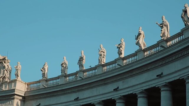 A panning shot of the impressive St. Peter's Square Colonnade in Vatican City, showing the giant columns and tourists strolling through the majestic covered architectural passage.
