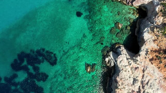 Overhead Shot tracing the cliffs of Plathiena in Milos, Greece. Showing the stunning crystal clear waters. Shot on a 4k at 60 fps on a DJI Mini 3 Pro in Raw Footage (uncolorgraded), D-Log film