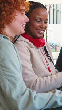 Multiracial friends laughing together using a smartphone
