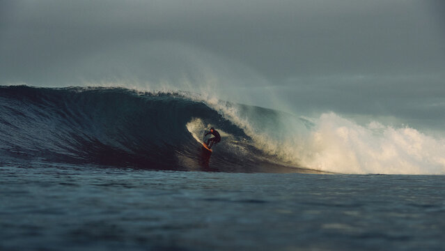 surfer large tubular wave sunrise atlantic ocean