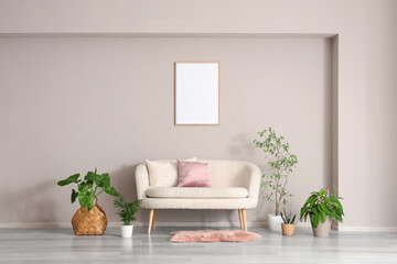 Naklejka premium Comfortable sofa and houseplants near beige wall in interior of living room