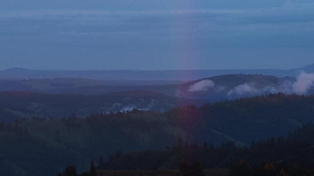 Aerial of low clouds over Wallowa Whitman national forest at blue hour with rainbow