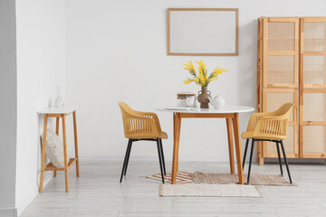 Fototapeta premium Table with chairs, cabinet and blank poster in interior of dining room