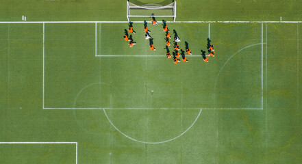 Aerial view of children in orange jerseys running across the soccer field during soccer practice at a sports park in Wuhan, China. © 晨啸 周