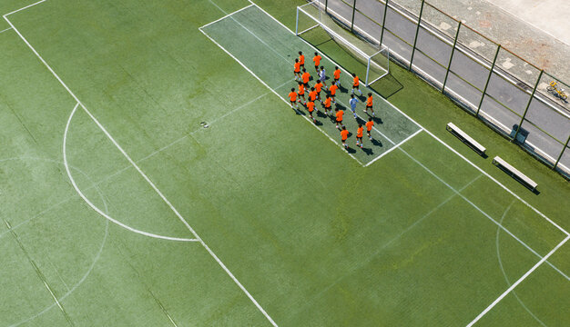 Aerial view of children in orange jerseys running across the soccer field during soccer practice at a sports park in Wuhan, China.