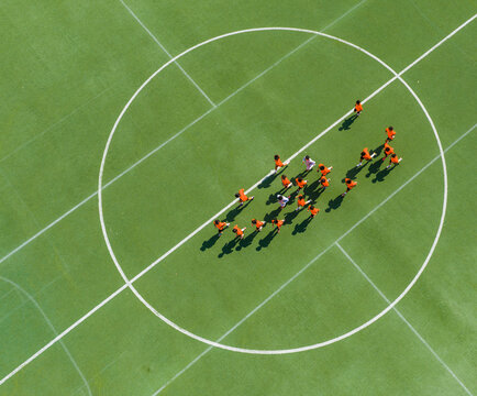 Aerial view of children in orange jerseys running across the soccer field during soccer practice at a sports park in Wuhan, China.