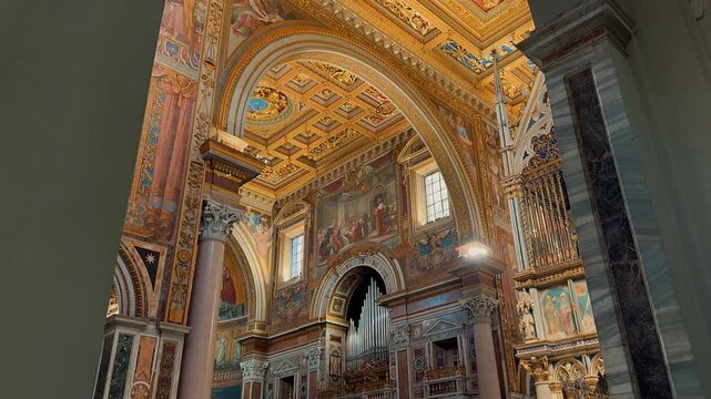 An incredible grand interior view showing the ornate golden ceiling, majestic marble columns, and exquisite religious artwork inside the historic Archbasilica of Saint John Lateran in Rome, Italy.

