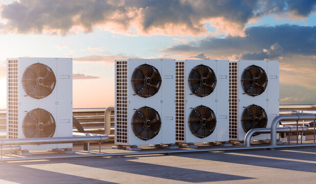 Industrial cooling systems. Rooftop HVAC condenser units provide commercial air conditioning and climate control at sunset