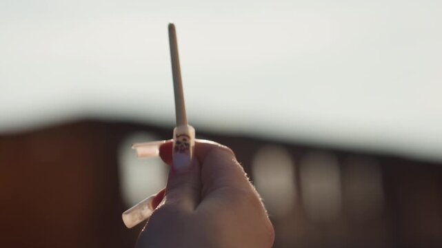 Closeup of brush and nails. Hand holds brush vertically as artist primes bristles carefully with water. Person expertly prepares brush for painting by moistening bristles close to sky