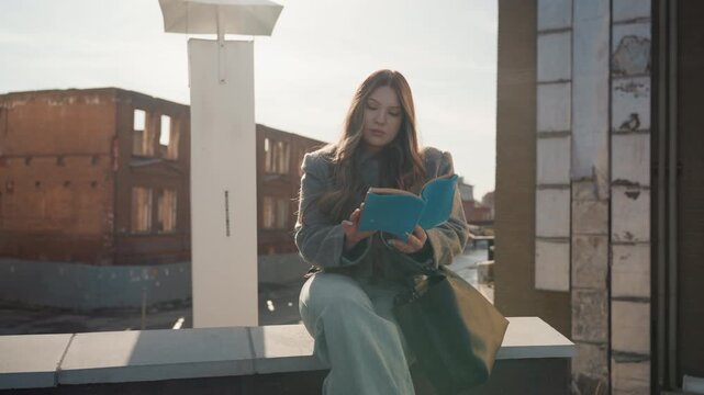Charming woman gracefully flips pages. Poised lady on top floor overlooking cityscape. Sophisticated rooftop scene featuring poised lady enjoying scenic city view while turning pages smoothly