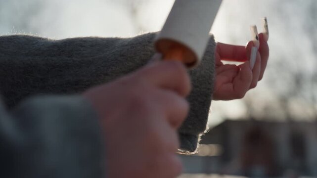 Hands rolling lint roller over sleeve, backlit winter yard with soft sunlight, closeup on fabric fibers and painted nails, gentle motion removes lint and debris, cozy morning routine with tactile