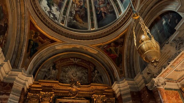 A breathtaking interior view of Sant Andrea della Valle in Rome, showcasing magnificent golden ornaments, high marble columns, and exquisite Baroque frescoes painted on the grand church ceiling.

