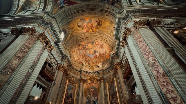 A breathtaking interior view of Sant Andrea della Valle in Rome, showcasing magnificent golden ornaments, high marble columns, and exquisite Baroque frescoes painted on the grand church ceiling.

