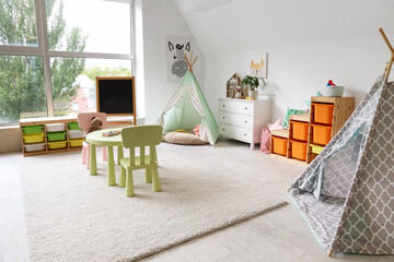 Interior of light playroom with toys, teepee and chalkboard in kindergarten © Pixel-Shot