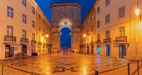 Rua Augusta Arch illuminated at blue hour in Commerce Square with traditional Portuguese mosaic pavement in Lisbon, Portugal. © Kavalenkava