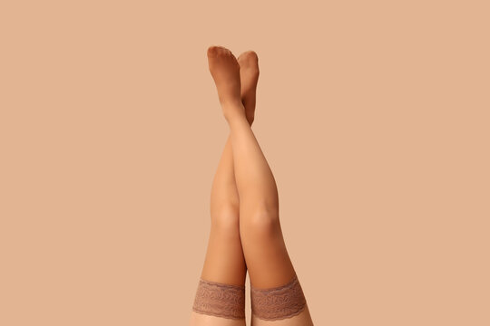 Legs of beautiful woman in stockings on beige background