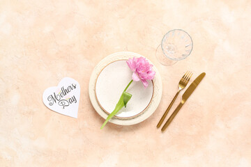 Naklejka premium Table setting with greeting card for Mother's day and flower on beige background