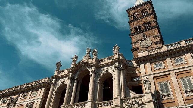 A stunning wide shot of the historic Basilica of Saint Mary Major in Rome, Italy, featuring its magnificent twin domes and the prominent obelisk against a clear sky.


