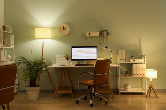 Workplace of programmer with modern computer and glowing lamps in office