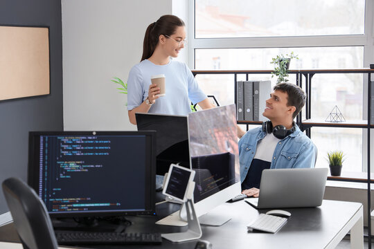 Young couple of programmers working at table in office