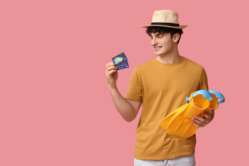 Young man in hat with flippers and credit card on pink background © Pixel-Shot