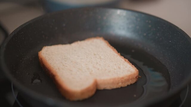 Toasting bread in soft glow. Gentle frying of bread in warm skillet. Quiet morning moment with bread warming on stove. Peaceful kitchen scene of bread gently browning over low heat