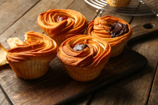 Board of tasty cruffins with chocolate and jam on wooden background