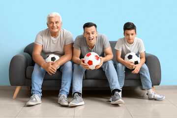 Little boy with his dad and grandfather watching football game near blue wall © Pixel-Shot