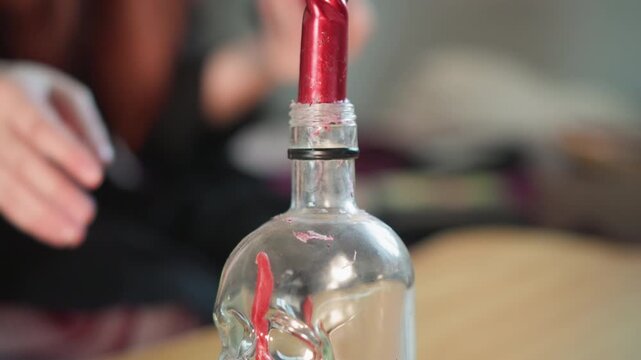 Mystic candle scene. Suspenseful scene with smoking candle and blurred figure in background. Atmospheric shot of glowing red candle enclosed in glass with skull charm and smoky surroundings