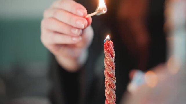 Hand lighting twisted candle with match, soft bokeh background, slow burn glow, closeup of wick and wax, woman performing intimate fortune telling ritual, moody ambient light suggesting divination