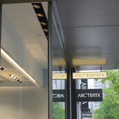 Naklejka premium wall mounted projecting signs outside Holt Renfrew and Arc'teryx, an outdoor clothing and equipment shop both at 50 Bloor St W, Toronto