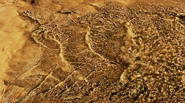Abstract water texture with light reflections and sand, Clear creek water over dry mud and rocky surface
