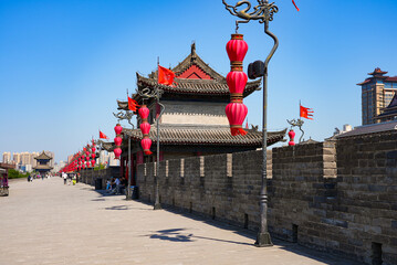 Perspective view of the wide paved path on top of the ancient Xi'an city wall with a historic watchtower and traditional red lanterns, Shaanxi, China © Alexandre ROSA
