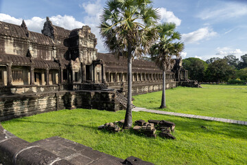 Fototapeta premium Angkor Wat, Siem Reap, Cambodia. The iconic temple complex, a UNESCO World Heritage site, is bathed in sunlight under a blue sky with scattered clouds.