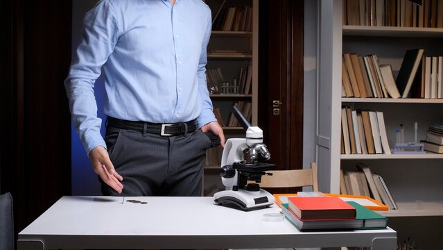 Scientist or student showing empty pockets while standing in a laboratory or library, symbolizing financial crisis, lack of funding for education, research, or scientific development