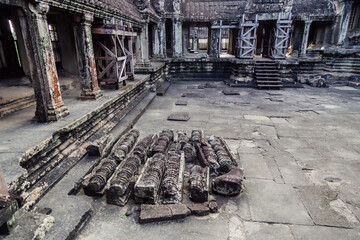 Fototapeta premium Ancient stone carvings lie scattered in the courtyard of Angkor Wat temple complex in Siem Reap, Cambodia. The temple is a UNESCO World Heritage site.