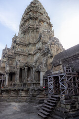 Fototapeta premium Angkor Wat temple complex in Siem Reap, Cambodia, showcases intricate Khmer architecture and bas-reliefs, with scaffolding indicating ongoing restoration efforts.