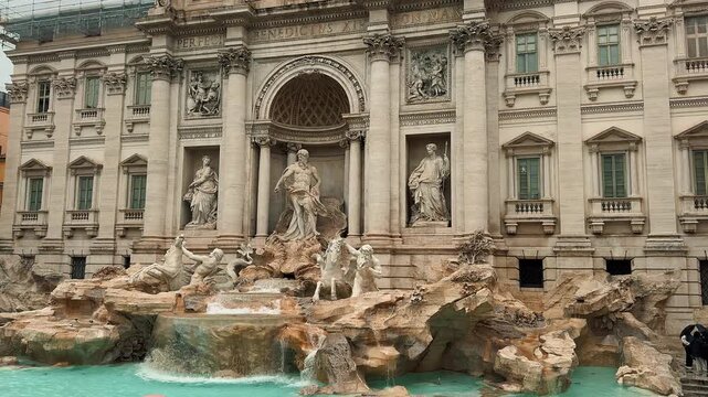 This beautiful panning video reveals the majestic architecture and exquisite baroque marble statues of the iconic Trevi Fountain in Rome, Italy, during a cloudy and rainy autumn afternoon.

