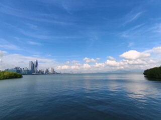Obraz premium Expansive panoramic seascape view of a distant modern city skyline across a tranquil blue bay