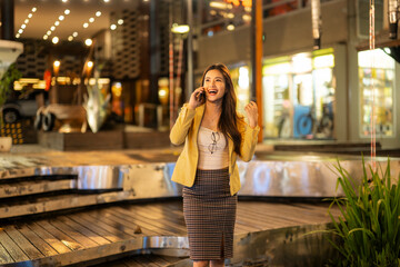 Fototapeta premium Excited businesswoman receiving good news on phone in urban setting at night