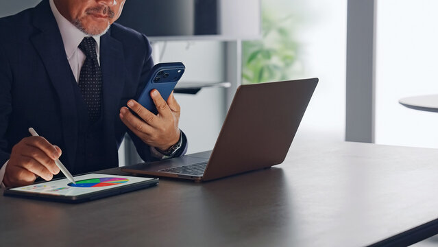 スマホとタブレットPCを使って作業する男性
