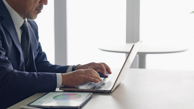 ノートパソコンとタブレットPCを使って作業する男性