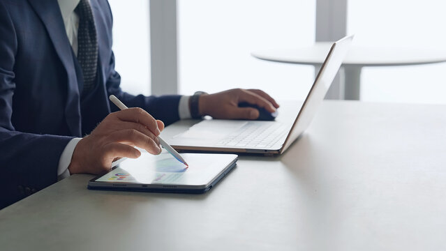 ノートパソコンとタブレットPCを使って作業する男性