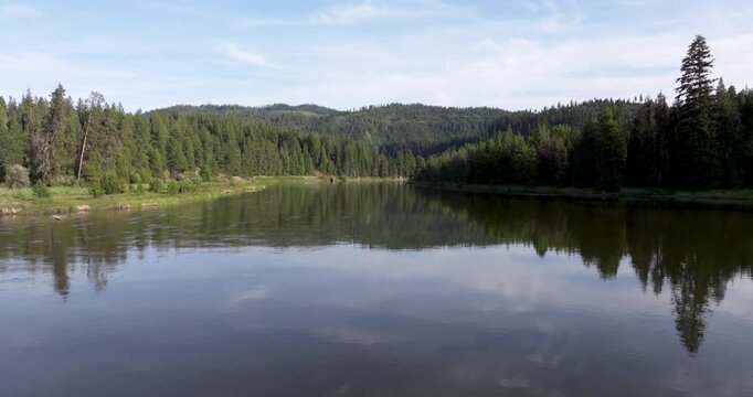 Clear water reflects blue sky and clouds