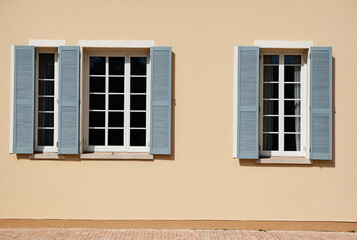 Obraz premium Traditional European building facade with elegant windows and blue wooden shutters