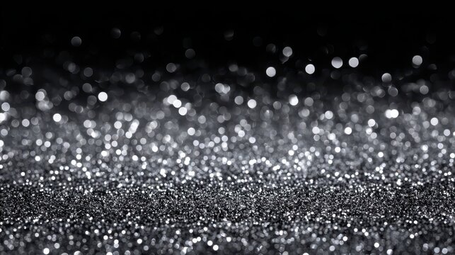Close-up of shimmering silver glitter with a dark background, creating a sparkling effect.