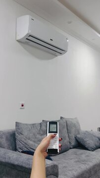 Turning off the air conditioner with a remote control, 9:16 vertical video, adjusting climate control, home comfort, stopping the cooling, modern HVAC system, lifestyle.