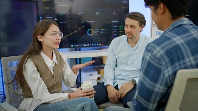Diverse business professionals sitting and discussing executive overview dashboard in modern office. Concept of team collaboration, data-driven decision making, business strategy, corporate planning.